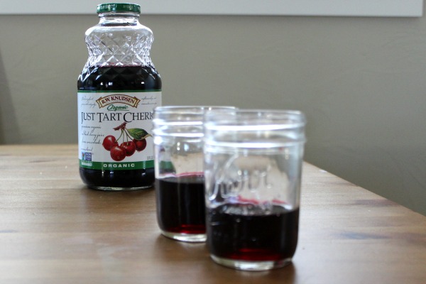 tart cherry juice to help kids sleep - a bottle in the background and two small mason jars with 2 oz of cherry juice in the front