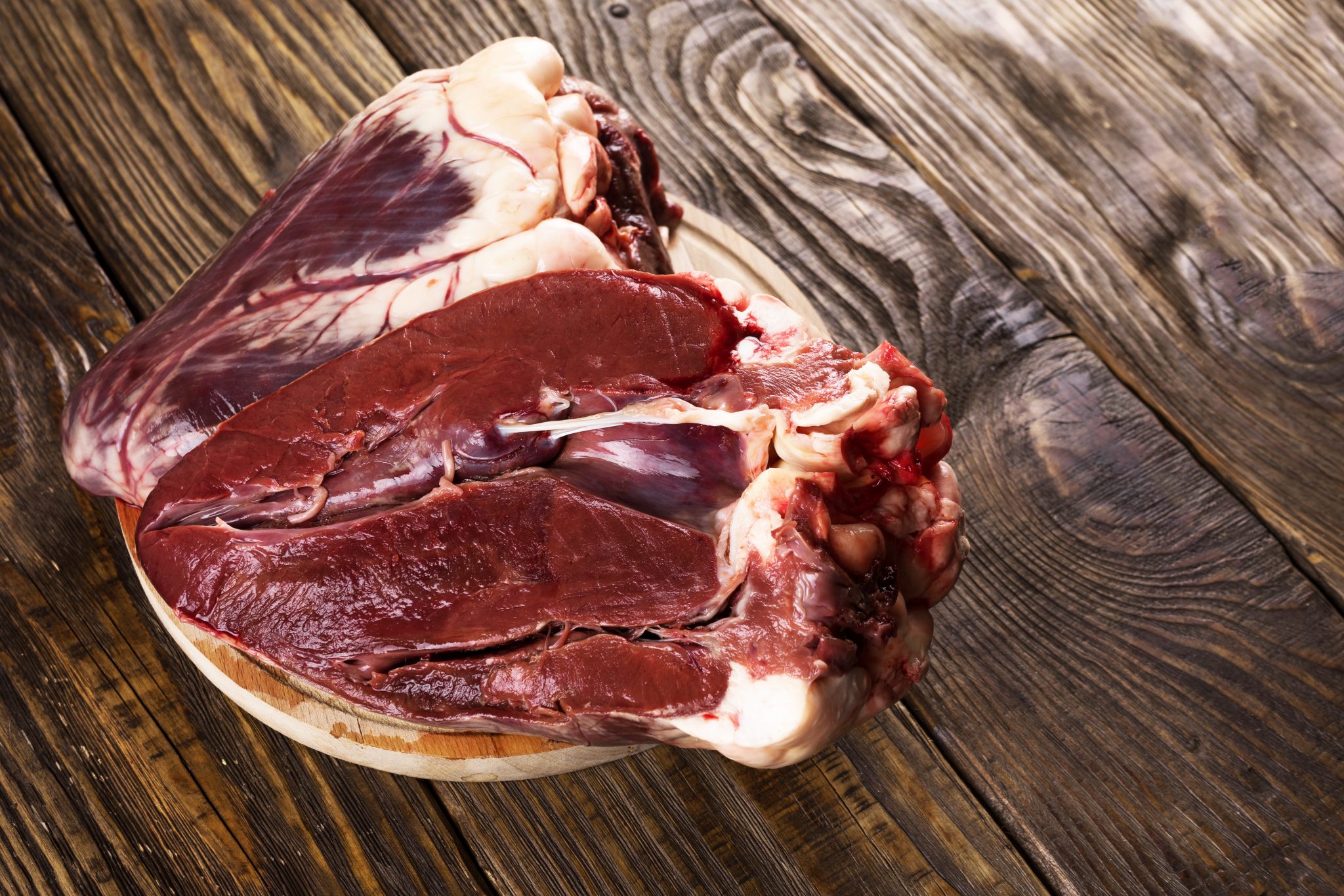 Beef Heart, raw on a wood background