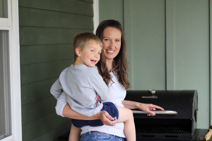 Mom grilling breakfast with a preschooler on her hip. 