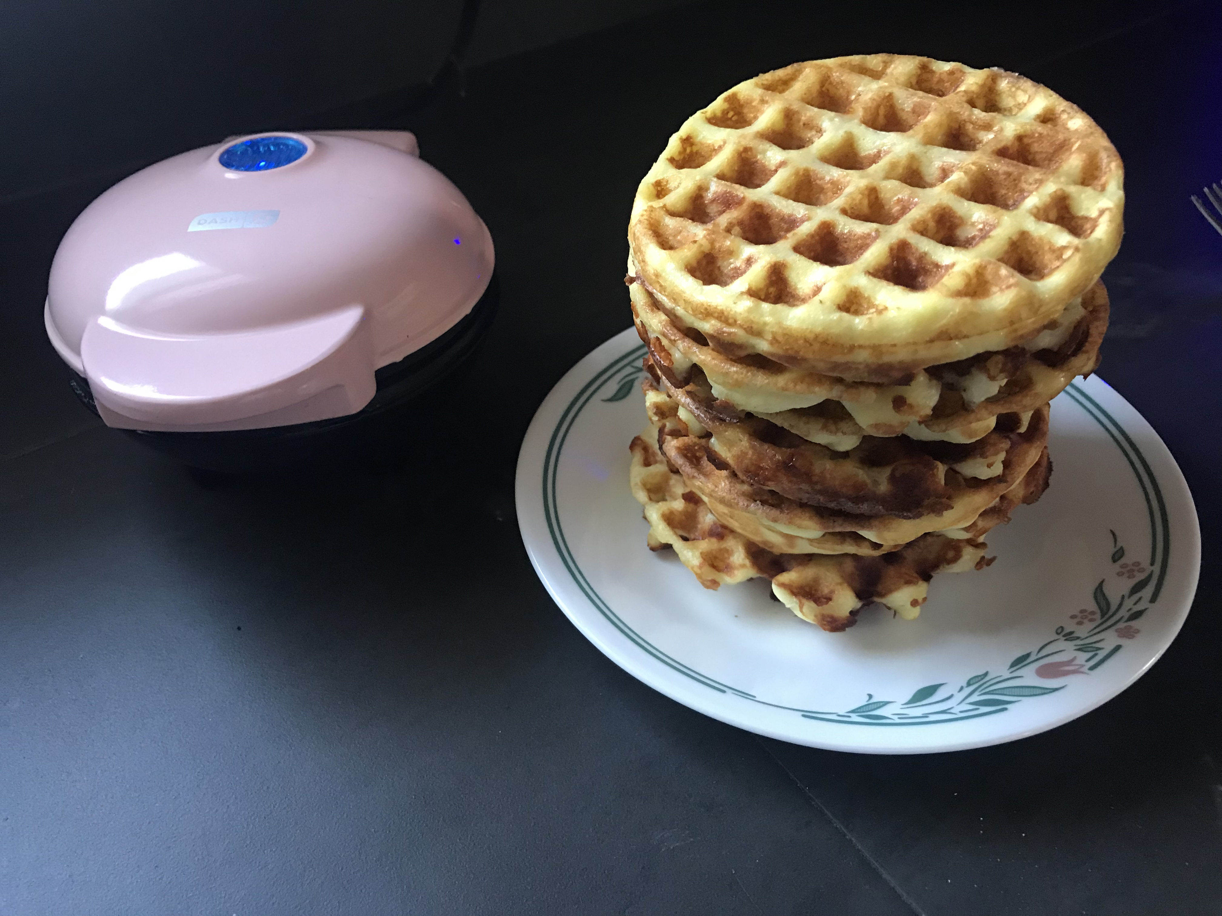 Stack of chaffles next to a mini waffle iron